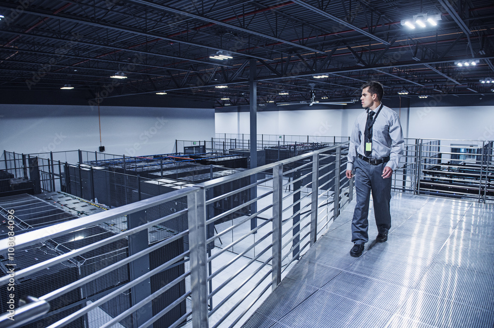 Hispanic businessman examining server room from balcony Hispanic businessman examining server room from balcony