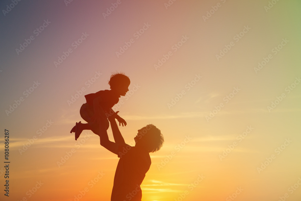 father and little son silhouettes play at sunset
