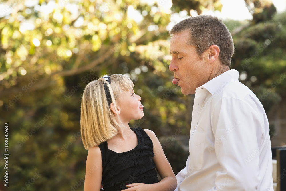 Caucasian father and daughter sticking out tongues Caucasian father and daughter sticking out tongues