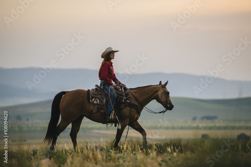 Cowgirl riding horse in a field photo