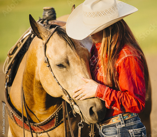 Caucasian cowgirl petting horse on ranch photo