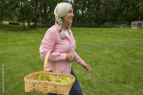 Caucasian woman carrying basket of vegetables in garden photo