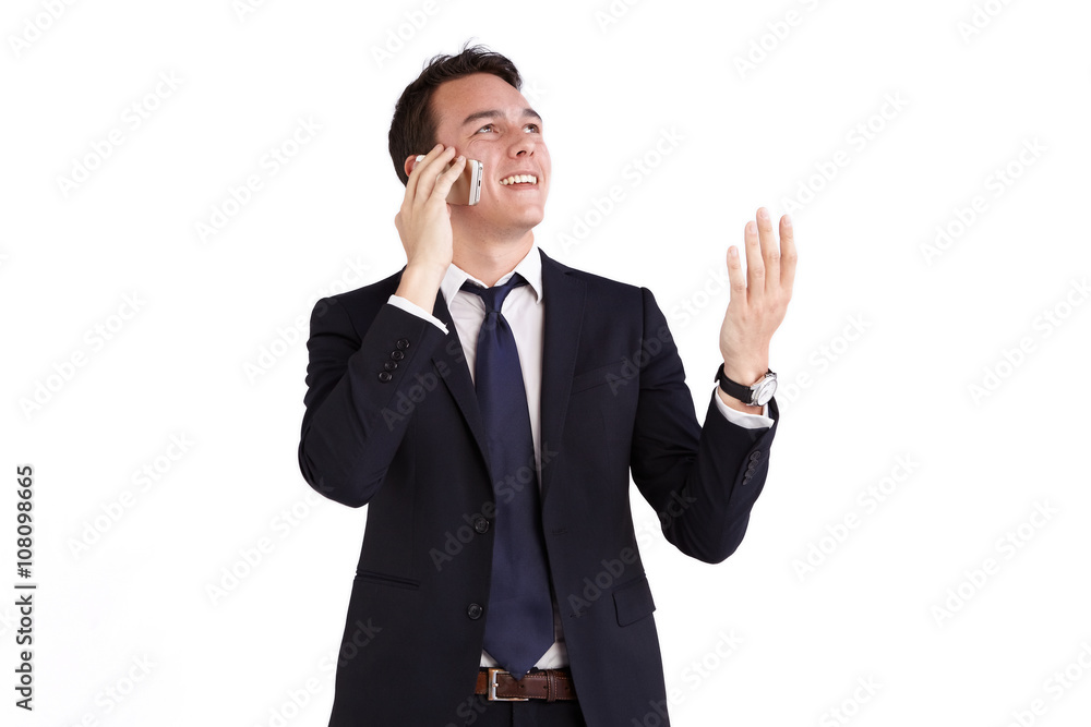 A young caucasian male businessman smiling with raised hand holding a mobile phone looking away from camera. A young caucasian male businessman smiling with raised hand holding a mobile phone looking away from camera.
