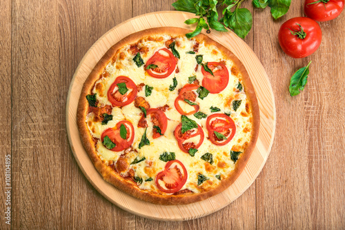 Pizza Margherita with tomatoes, mozzarella and basil on a wooden board, flat lay, top view