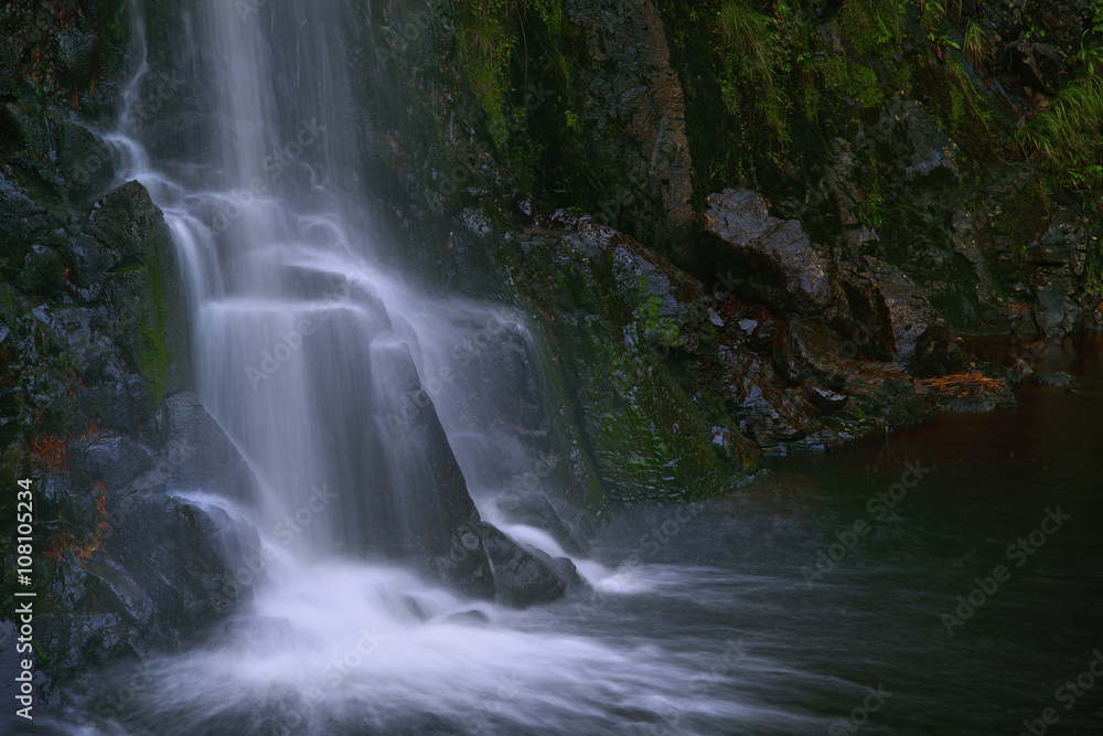Waterfall flowing over rocky cliff Waterfall flowing over rocky cliff