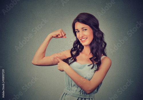 Fit young healthy model woman flexing muscles showing her strength