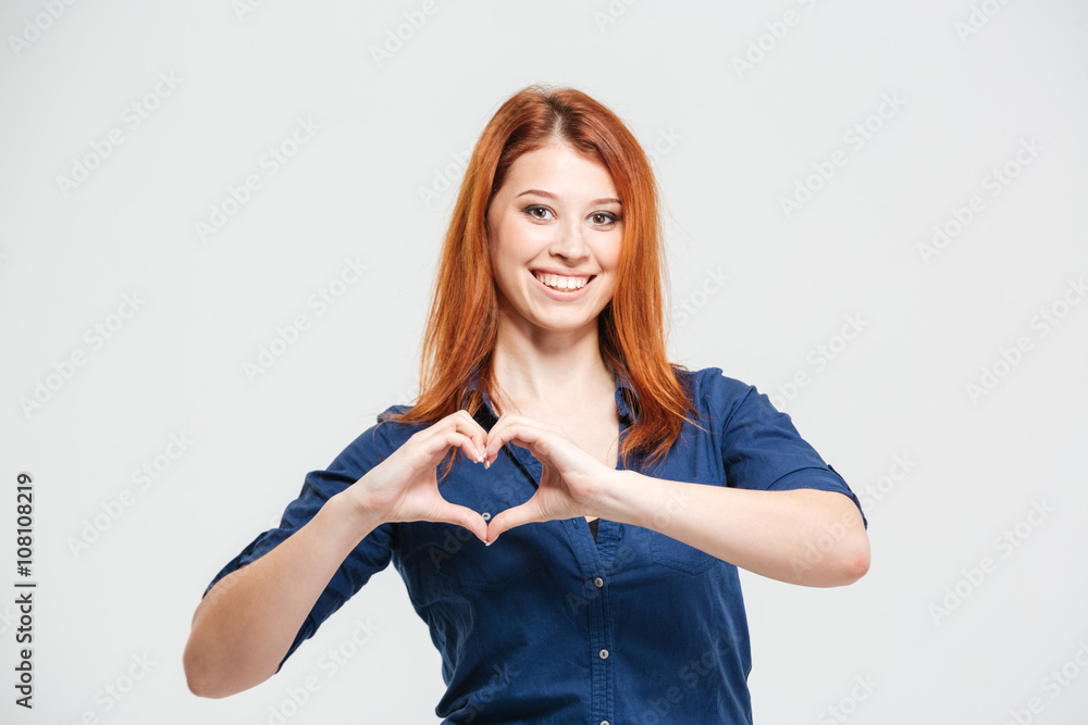 Cheerful beautiful redhead young woman making heart by hands Cheerful beautiful redhead young woman making heart by hands