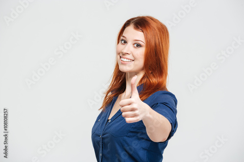 Quadro su tela Cheerful attractive redhead young woman showing thumbs up