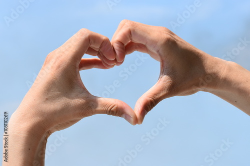 Concept or conceptual human male or man and woman hands in love, symbol of heart over blue sky background © toowaretmukat
