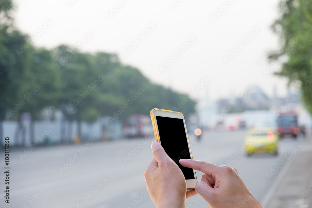 Man use mobile phone waiting for the bus with blurred Traffic ba Man use mobile phone waiting for the bus with blurred Traffic ba