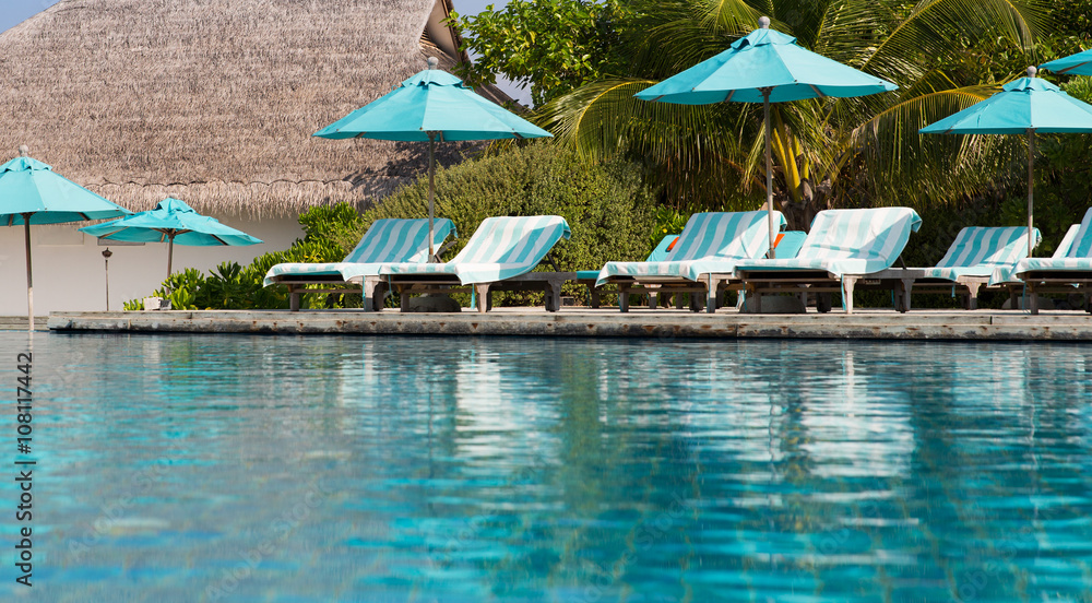 parasol and sunbeds by sea on maldives beach