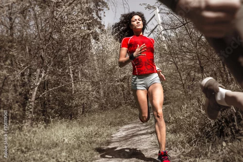 Obraz Młoda kobieta w czerwonej odzieży sportowej działa w parku.