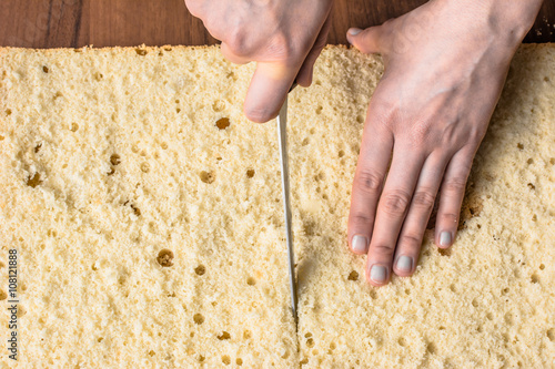 Cutting sponge cake on layers. Preparing a torte cake, detail of