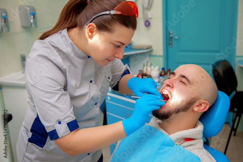 Female dentist treats teeth patient
