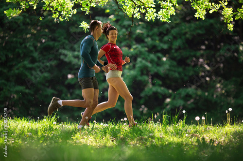 Fototapeta Naklejka Na Ścianę i Meble -  Amidst nature's beauty, a young couple enjoys a refreshing jogging, savoring the fresh air and beautiful spring surroundings.