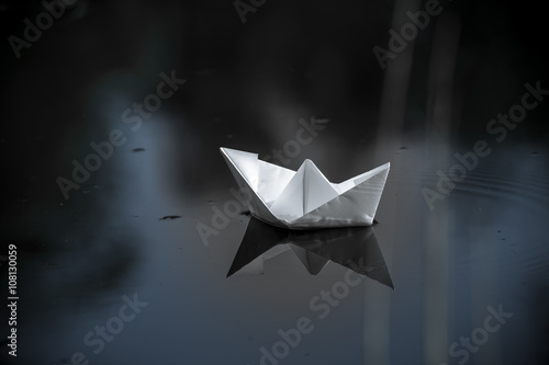 paper boat sailing on water surface at sunset
