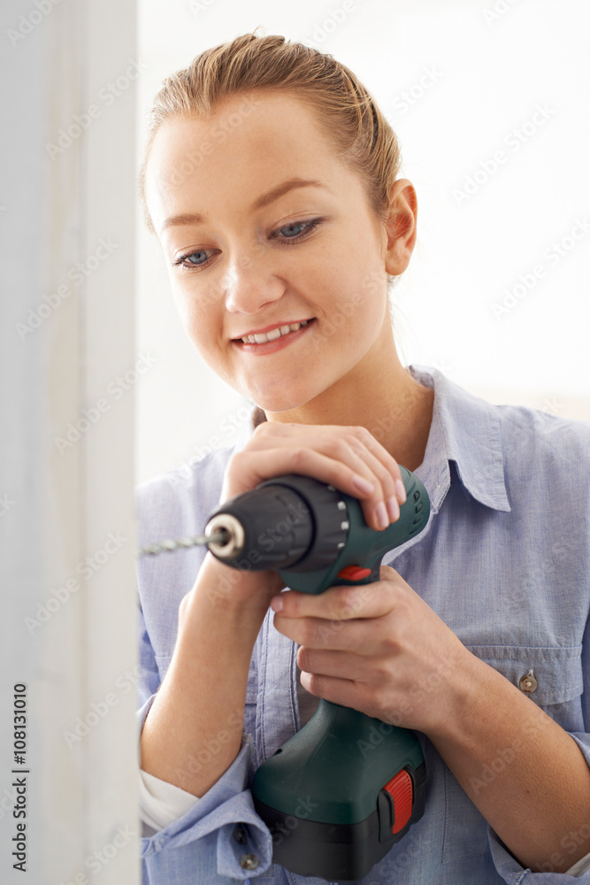 Fototapeta premium Young Woman Using Electric Drill In House Rennovation Project