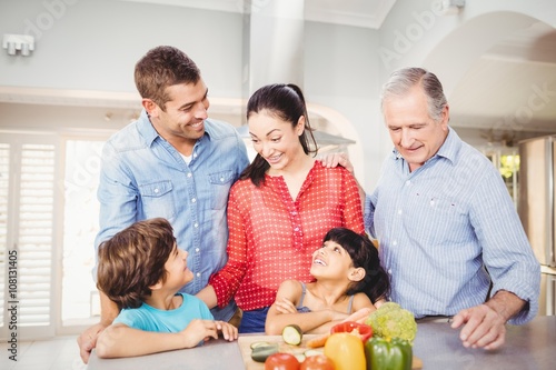 Cheerful family standing by kitchen table