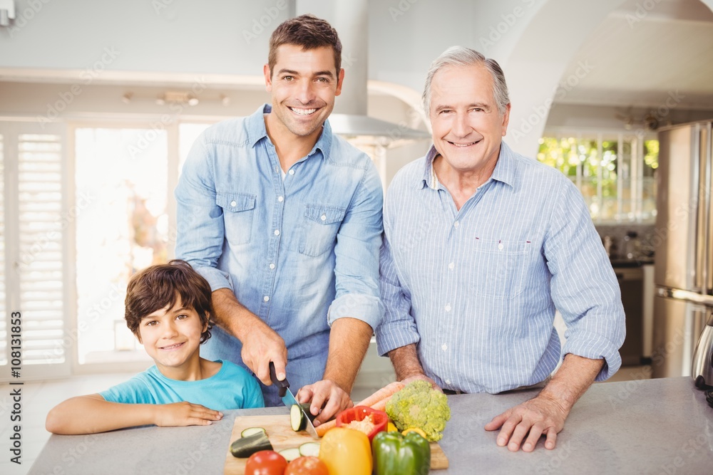 Happy man chopping vegetables with son and father Happy man chopping vegetables with son and father