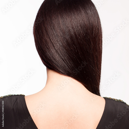 Young brunette black dress stands back, on white background