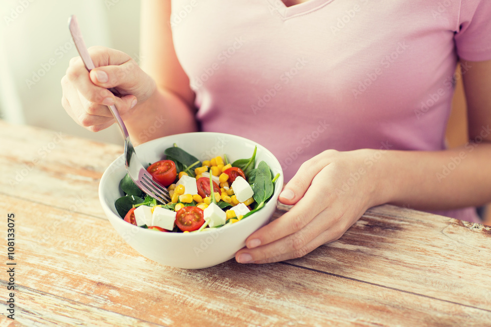 close up of young woman eating salad at home close up of young woman eating salad at home
