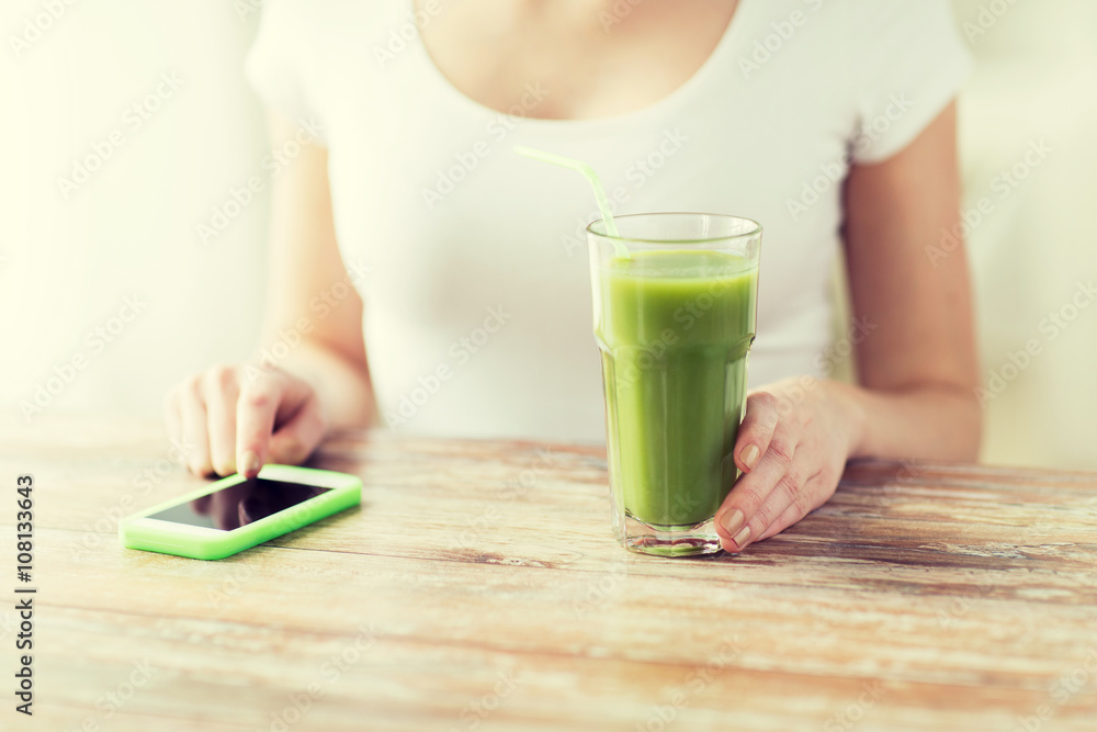 close up of woman with smartphone and green juice close up of woman with smartphone and green juice