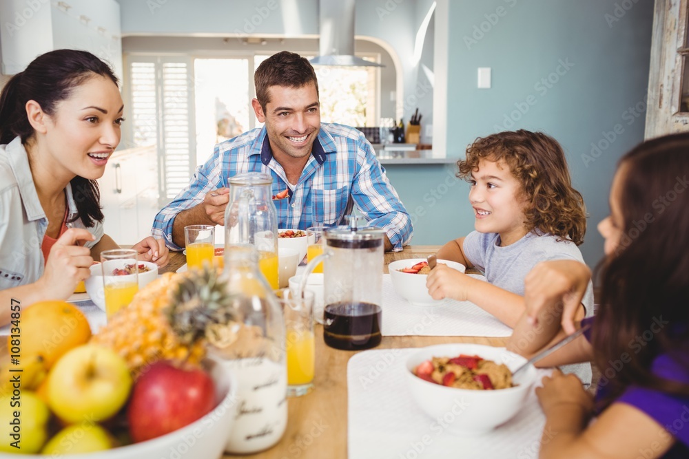 Cheerful family eating breakfast at table