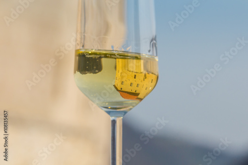 Glass of sparkling white wine and castle reflection in it.