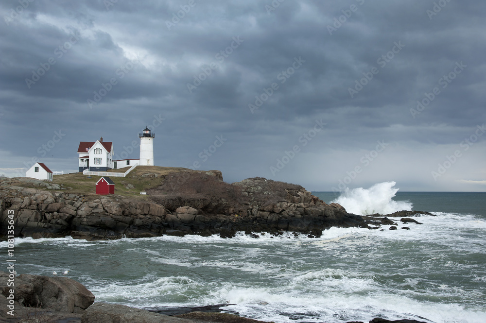 Sun Breaks Through Storm Clouds Over Nubble Lighthouse with Waves Crashing in Maine