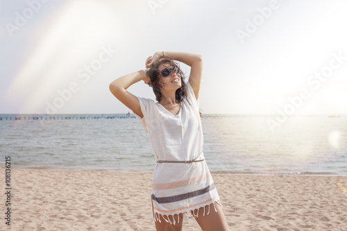 Woman in a tunic on the beach happy smiles and relaxes in the su photo