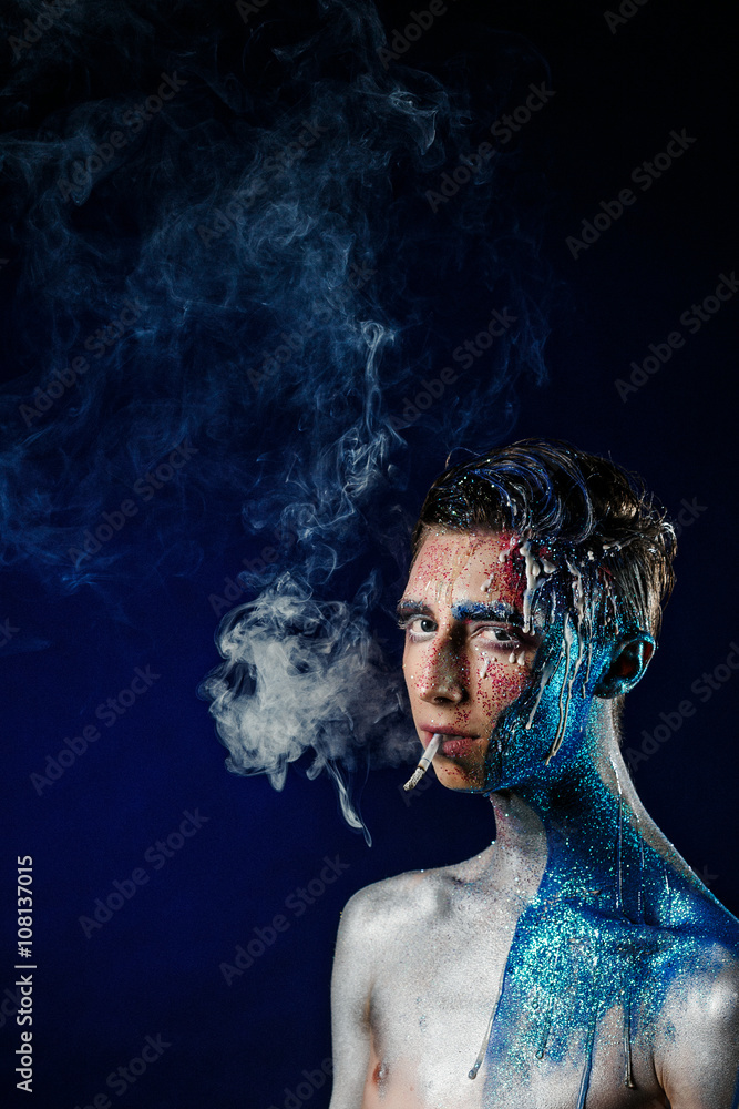 Crazy young man with face art smoking and enjoying. Freak person Crazy young man with face art smoking and enjoying. Freak person