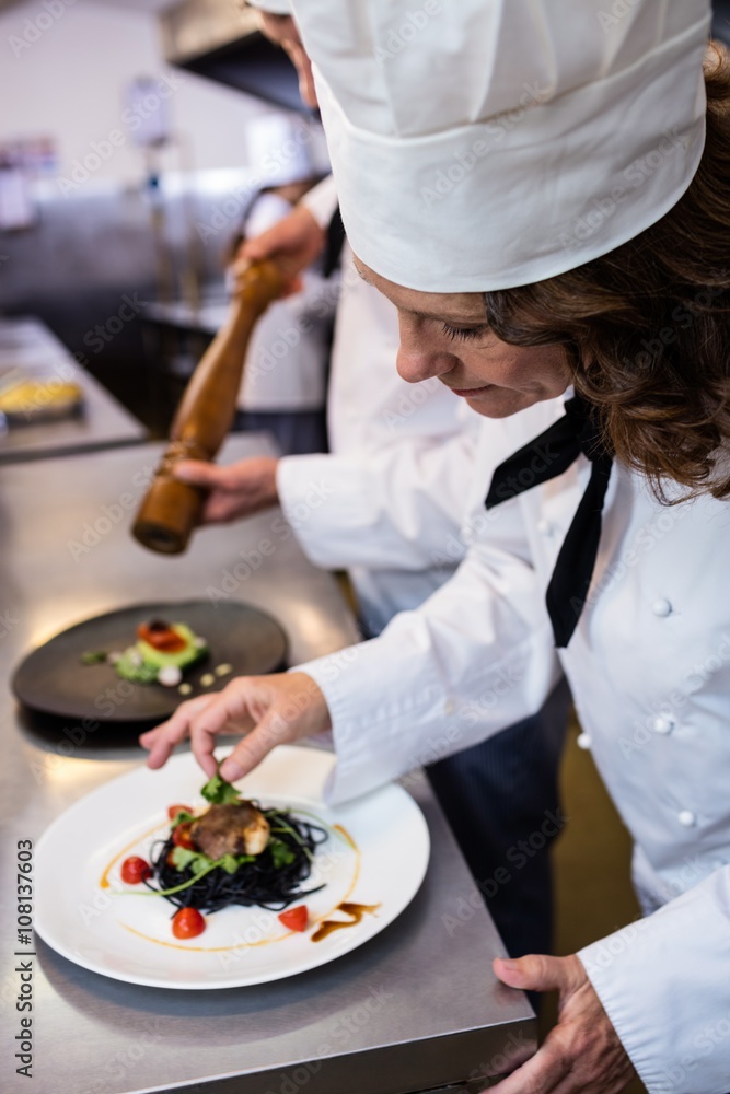 Female chef garnishing meal on counter