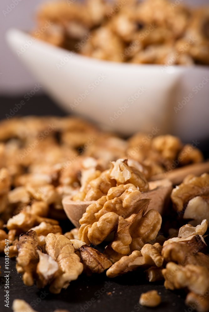 Walnuts spilled on black slate stone with bowl and spoon Walnuts spilled on black slate stone with bowl and spoon