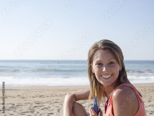 happy pretty woman smiling in the beach wearing a pink top with the sea and horizon in the background,
