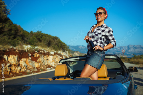 Beautiful pin up woman sitting in cabriolet, enjoying trip on lu