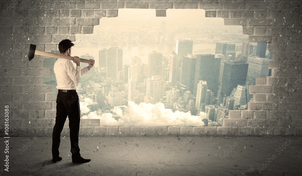 Business man hitting wall with hammer on city view Business man hitting wall with hammer on city view