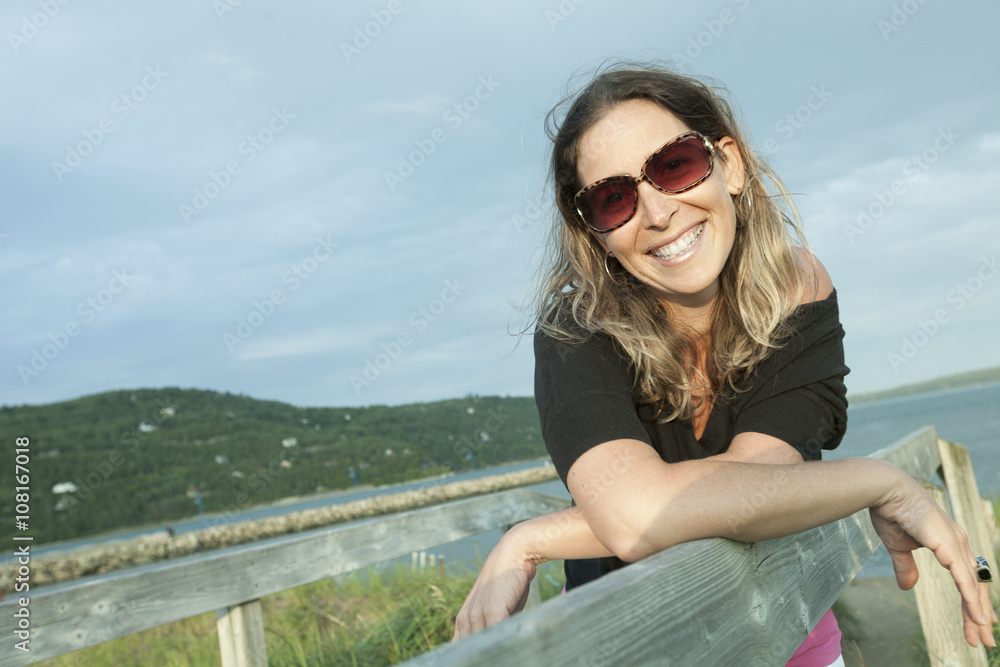 Portrait of model posing outdoors on the beach against fence Portrait of model posing outdoors on the beach against fence