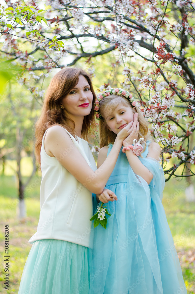 Young caucasian woman and her little daughter in spring garden Young caucasian woman and her little daughter in spring garden