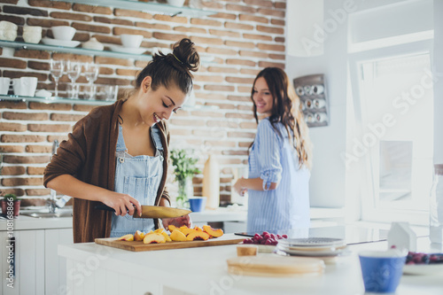 Caucasian women chopping fruit in kitchen photo