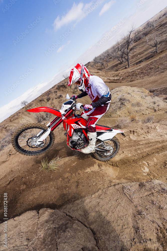 Motorcyclist riding dirt bike on hillside Motorcyclist riding dirt bike on hillside