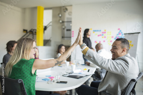Business people high-fiving in office meeting
