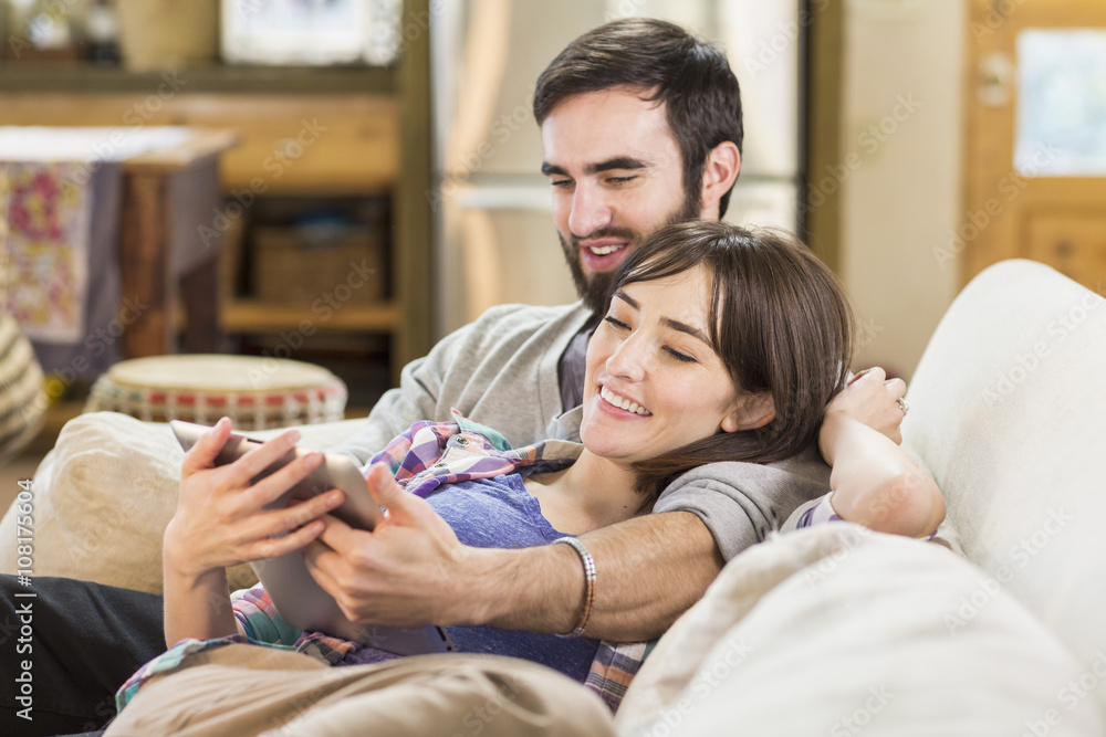 Hispanic couple using digital tablet on sofa Hispanic couple using digital tablet on sofa