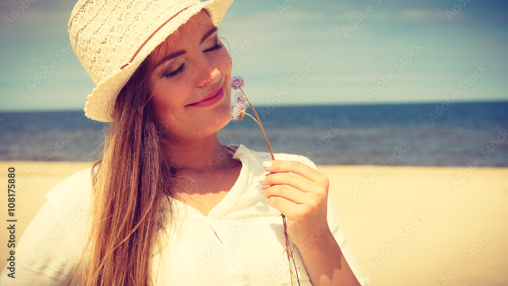 Smiling girl with flower on beach - obrazy, fototapety, plakaty 