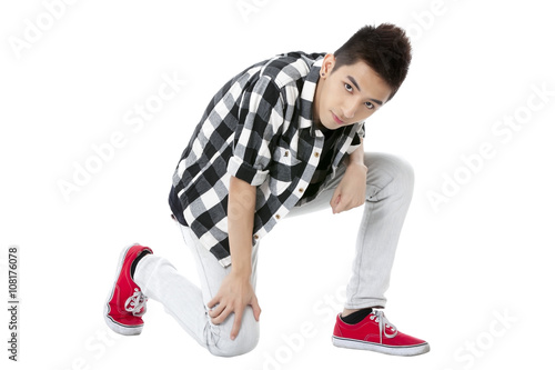 teenage guy kneeling while looking at the camera