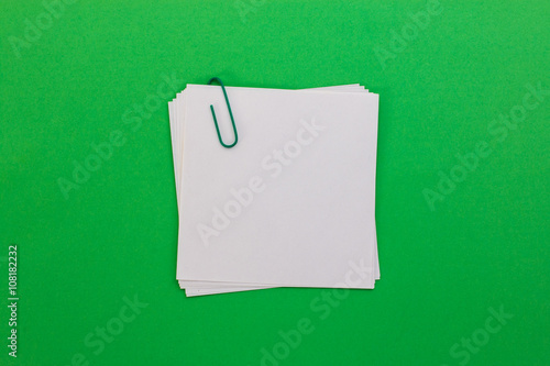 white sheet of paper with green paper clip on a green background