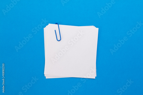 white sheet of paper with blue paper clip on a blue background
