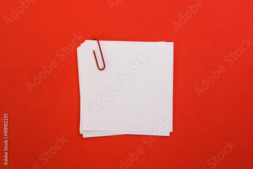 white sheet of paper with red paper clip on a red background