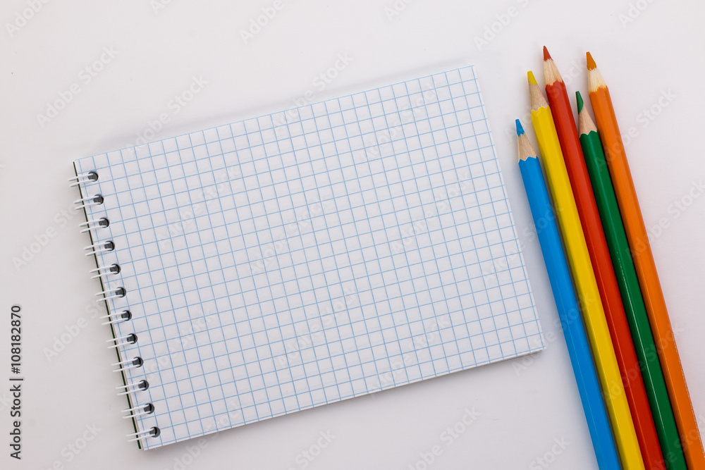 notebook and colored pencils on a white background notebook and colored pencils on a white background