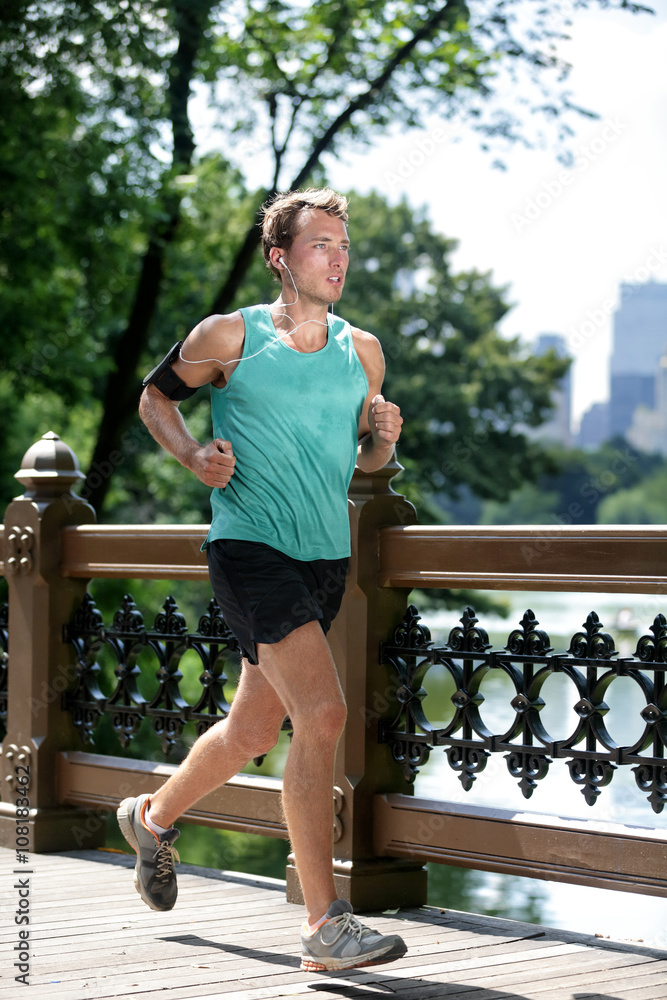 New York City runner running listening to music with smartphone armband.  Athletic young man exercising cardio using mobile phone app and earphones  for workout in Central Park. Stock Photo | Adobe Stock