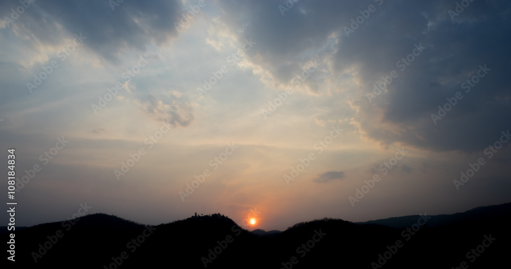 Sunset in cloudy sky with silhouette mountain view